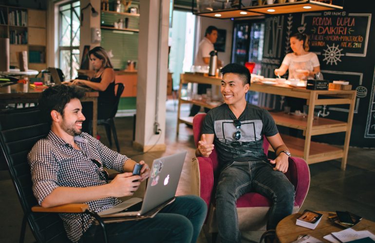 two men laughing white sitting on chairs