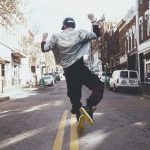 man jumping on the middle of the street during daytime