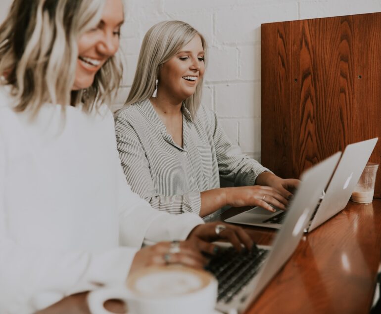 two women using laptops