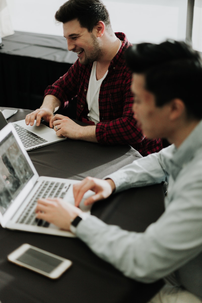 Photo by Priscilla Du Preez 🇨🇦 a couple of men sitting at a table with laptops